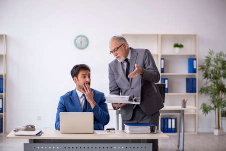 Old male boss and young male employee working in the officeの写真素材