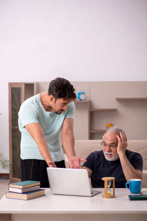 Grandfather and grandson at home with computerの写真素材