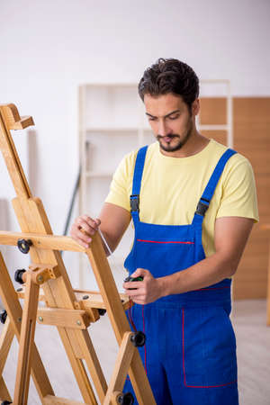 Young male repairman repairing easel at homeの写真素材