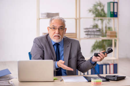 Old male employee working at workplaceの写真素材
