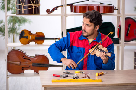 Young man repairing musical instruments at workshopの写真素材