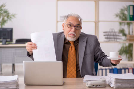Old male employee drinking coffee during breakの写真素材