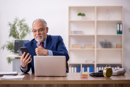 Old male employee working at workplaceの写真素材