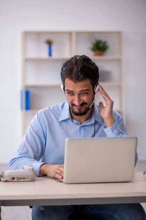 Young male call center operator working at his deskの写真素材