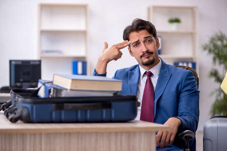 Young male employee preparing for trip at workplaceの写真素材