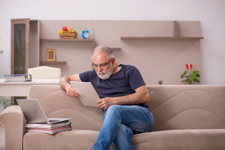 Old male employee working from home during pandemicの写真素材