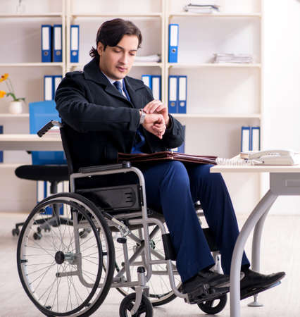 Young male employee in wheelchair working in the officeの写真素材