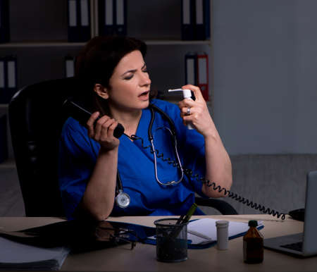 Aged female doctor working at night shiftの写真素材