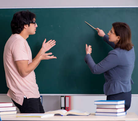 Old female teacher and male student in the classroomの写真素材