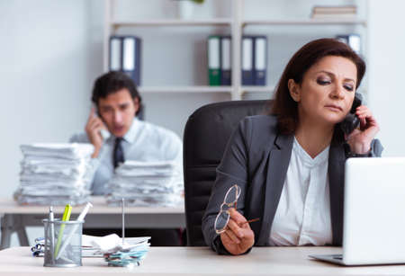 Old female boss and young male employee in the officeの写真素材