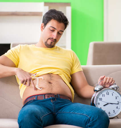 Man measuring body fat with calipers in time management conceptの写真素材