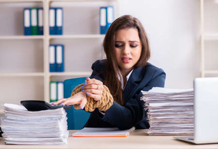 Young beautiful employee tied up with rope in the officeの写真素材