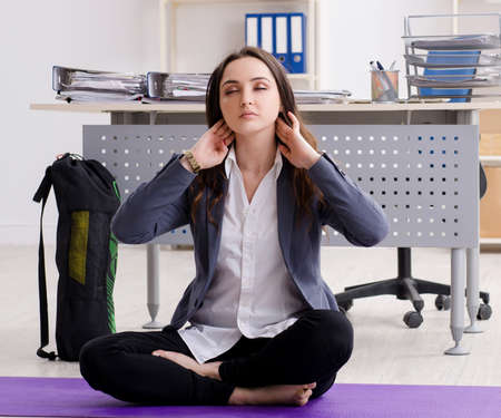 Female employee doing sport exercises in the officeの写真素材