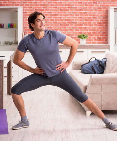 Young handsome man doing sport exercises at homeの写真素材