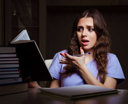 Young female student preparing for exams late at homeの写真素材