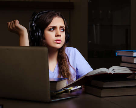 Young female student preparing for exams late at homeの写真素材
