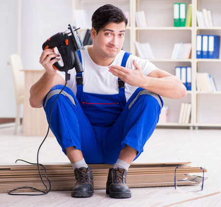 Young worker working on floor laminate tilesの写真素材