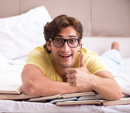 Young student studying in bed for examsの写真素材