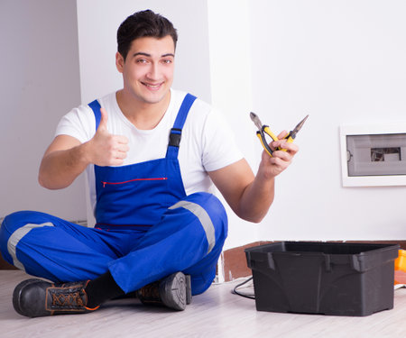 Young electrician working on socket at homeの写真素材