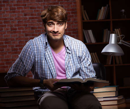 Young handsome student preparing for exams at nightの写真素材