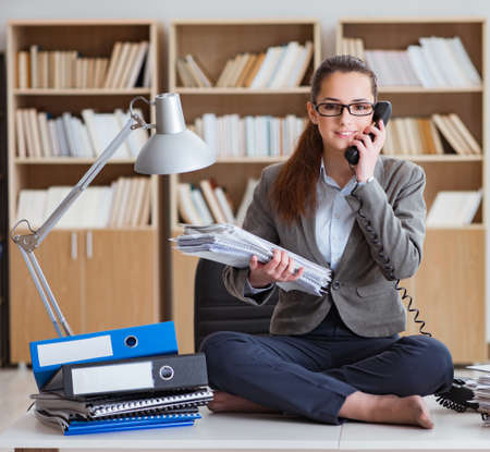 Busy angry businesswoman sitting on the desk in officeの写真素材