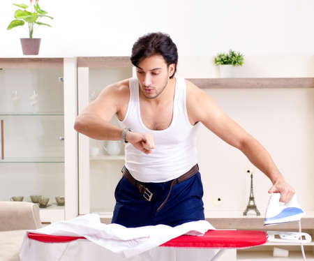 Young man ironing in the bedroomの写真素材