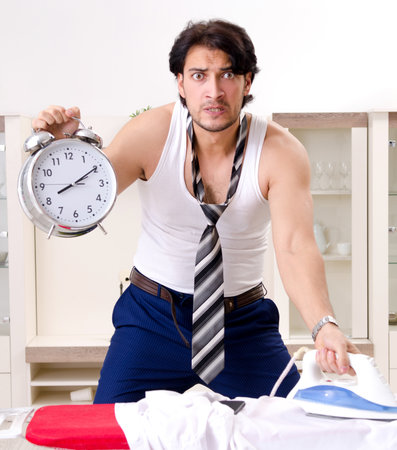 Young man ironing in the bedroomの写真素材