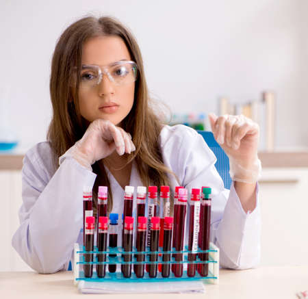 Young beautiful lab assistant testing blood samplesの写真素材