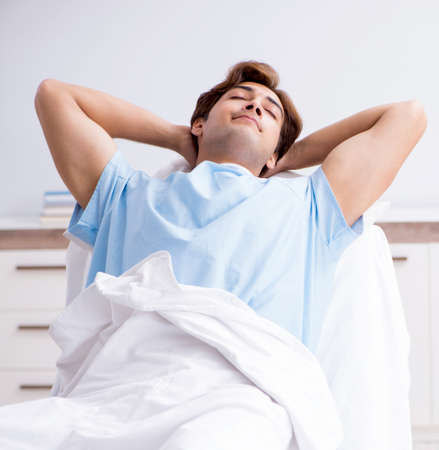 Young male patient lying on couch in hospitalの写真素材
