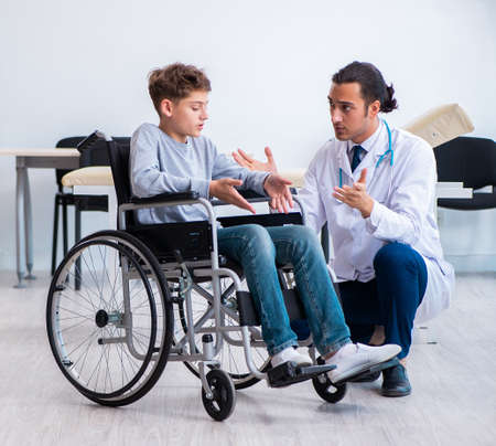 Young male doctor pediatrist and boy in wheel-chairの写真素材