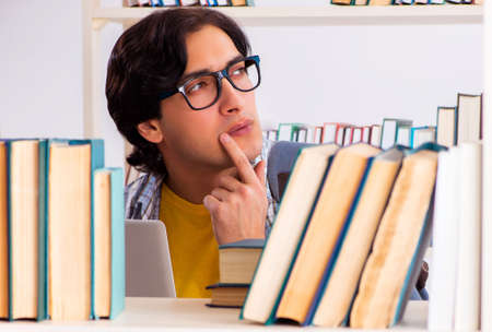 Male student preparing for exams at libraryの写真素材