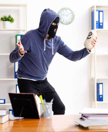 Male thief in balaclava in the officeの写真素材