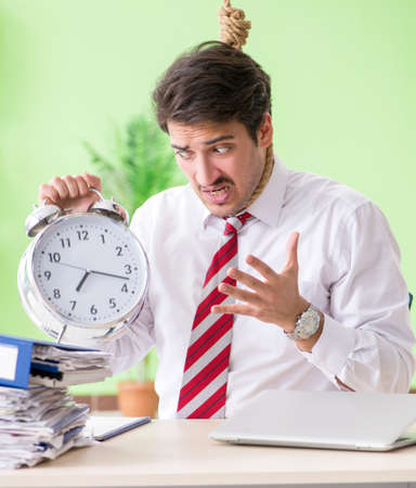 Despaired businessman thinking of suicide in the officeの写真素材