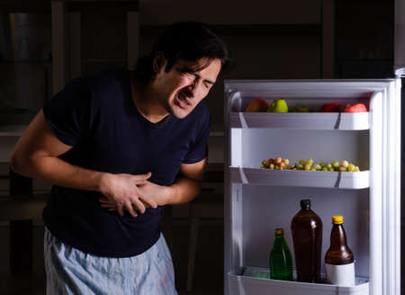 Man breaking diet at night near fridgeの写真素材