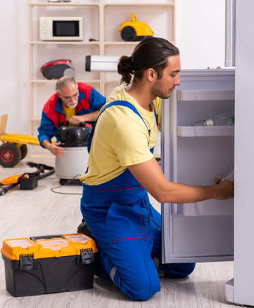 Two contractors repairing fridge at workshopの写真素材