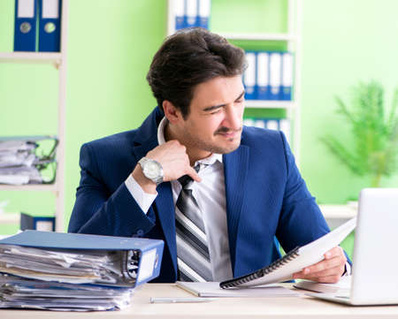 Businessman unhappy with excessive work sitting in the officeの写真素材
