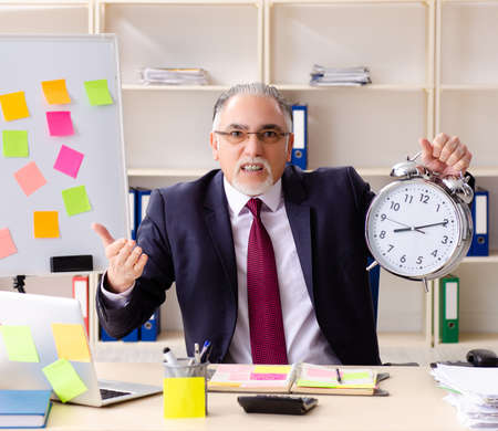 Aged man employee in conflicting priorities conceptの写真素材