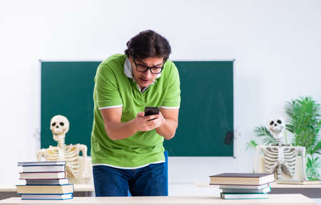 Funny male student in the classroom with skeletonの写真素材