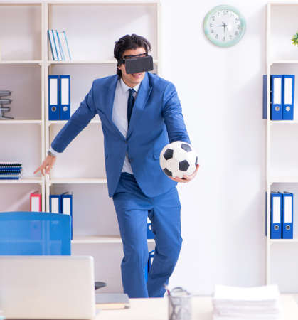 Young handsome businessman playing soccer with virtual glassesの写真素材