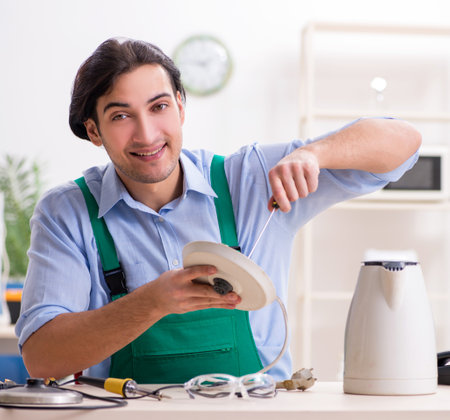 Young man repairing kettle in service centreの写真素材