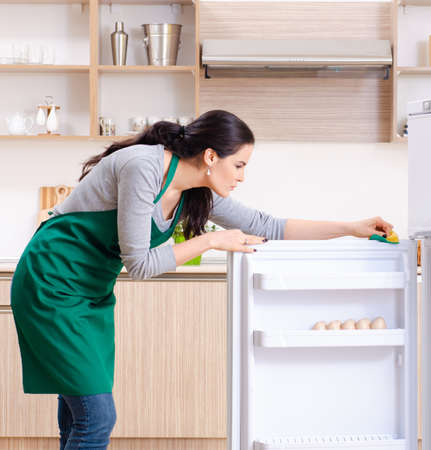Young woman cleaning fridge in hygiene conceptの写真素材