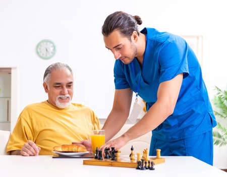 Young male doctor visiting old patient at homeの写真素材