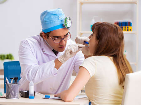 Young woman visting male doctor otolaryngologistの写真素材