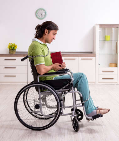 Young male invalid in wheel-chair suffering at homeの写真素材