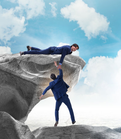 Businessman offering helping hand to falling colleagueの写真素材