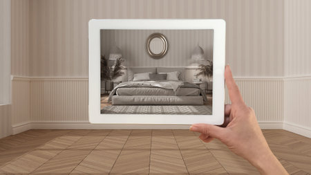 Augmented reality concept. Hand holding tablet with AR application used to simulate furniture and design products in empty interior with parquet floor, classic bedroom with decorsの写真素材