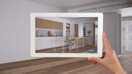 Augmented reality concept. Hand holding tablet with AR application used to simulate furniture products in custom architecture design, black ink sketch, modern kitchen and dining roomの写真素材