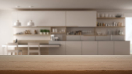 Empty wooden table, desk or shelf with blurred view of modern white kitchen with cabinets and dining table with chairs, decors and accessories, modern interior design conceptの写真素材