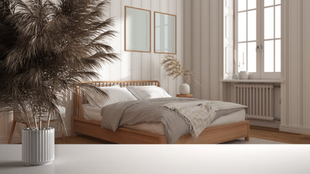 White table top or shelf with straws, dry plants, ornament, ears, sheaf, branch in vase, over wooden bedroom with frame mock up and wallpaper, modern minimal interior designの写真素材