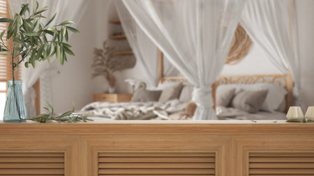 Wooden table top, cabinet, panel or shelf with shutters close up. Olive branch in vase and candles. Blurred background with bohemian bedroom with canopy bed, boho styleの写真素材